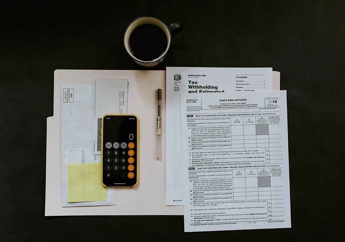 Des formulaires administratifs, une calculatrice et un stylo sur un bureau